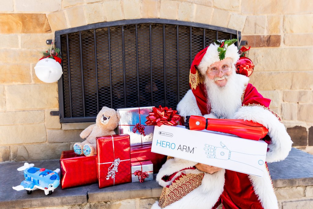 Santa Mike Tindall, a US Navy veteran and amputee wearing a festive red bionic arm, suits up in his Santa costume while holding a box of presents