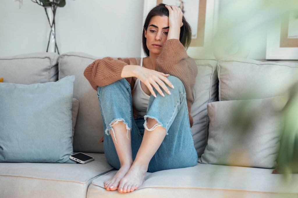 The shot of the young woman in depression flooding while sitting in bed at home